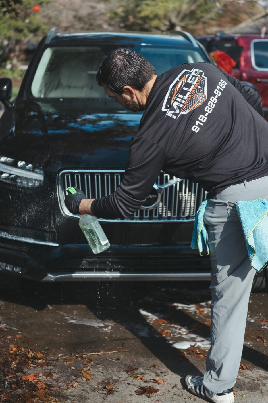 Detailing the grille and front end of a Volvo SUV by hand during a Tulsa mobile car detail