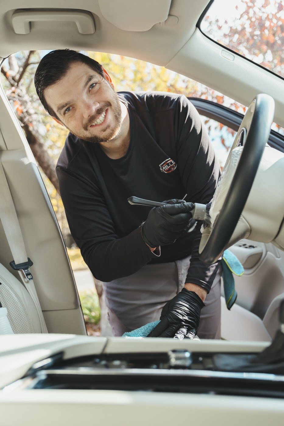 Detailing a steering wheel and dashboard controls with a brush during an interior detail