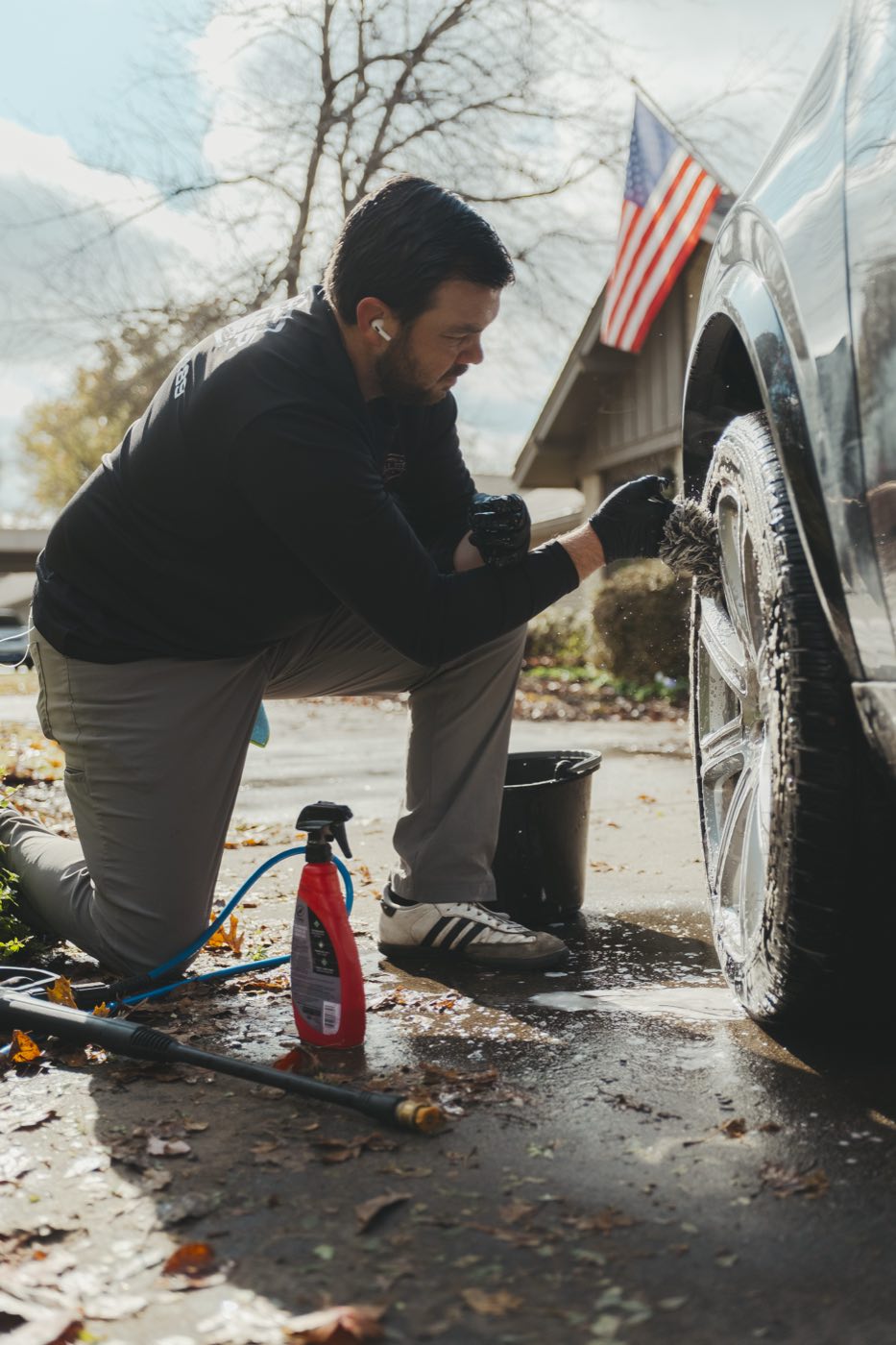 Scrubbing a tire sidewall by hand with a brush during a mobile detail in a Tulsa driveway