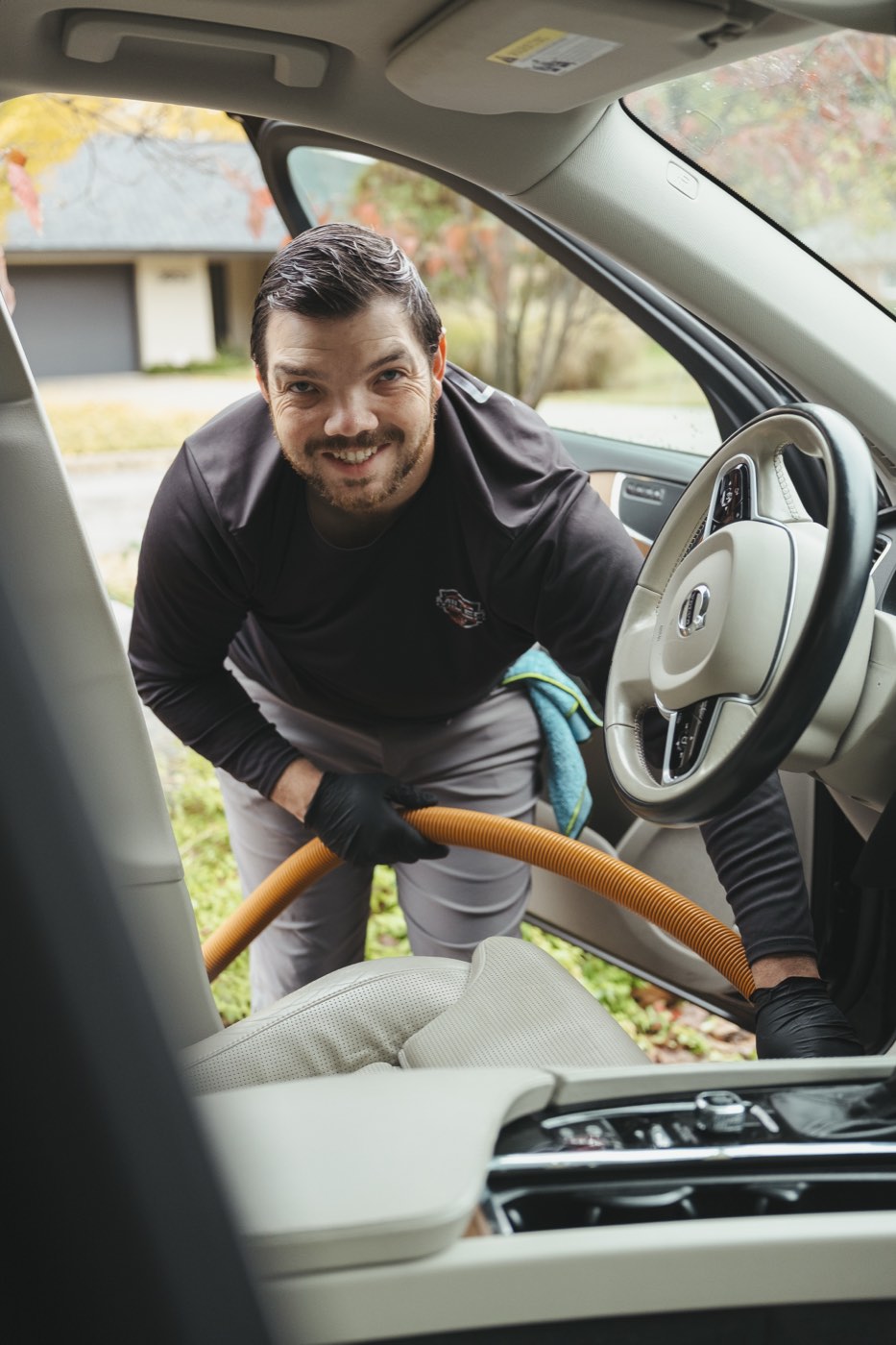 Alex Miller vacuuming the front seat of a car during an interior detail in Tulsa